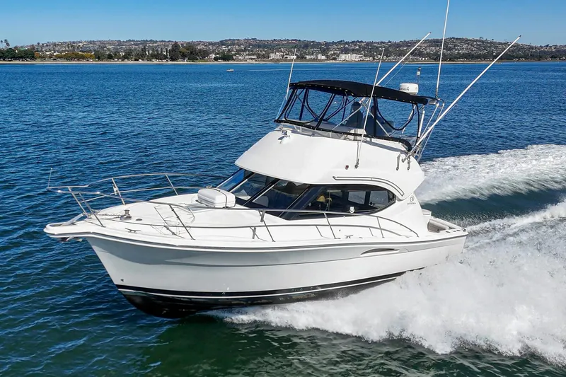 Slide: The Image of 2006 Riviera 33 Open Flybridge cruising on blue water, showcasing sleek design and performance. - 2