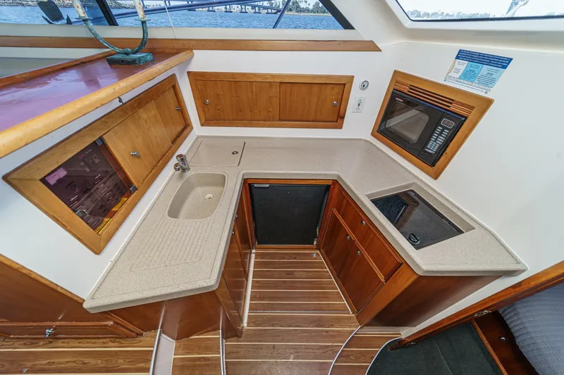 Slide: The Image of 2006 Riviera 33 Flybridge yacht kitchen with sink, microwave, and wooden cabinetry. - 30
