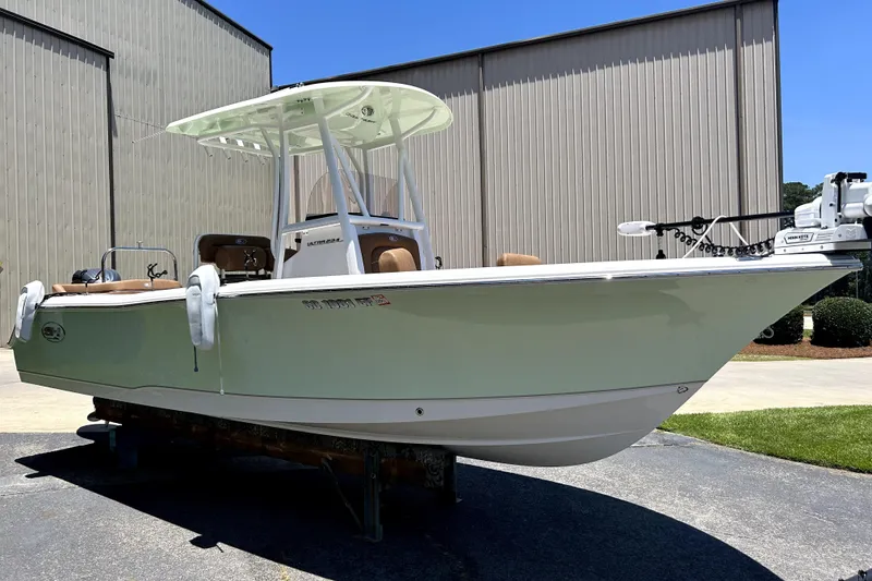 Slide: The Image of 2024 Sea Hunt Ultra 234 boat displayed outdoors near a warehouse. - 3