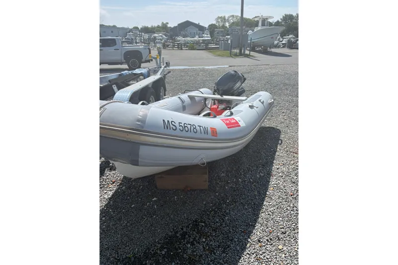 Slide: The Image of 2016 Zodiac Cadet RIB 340 PVC inflatable boat on gravel lot, for sale sign visible. - 2