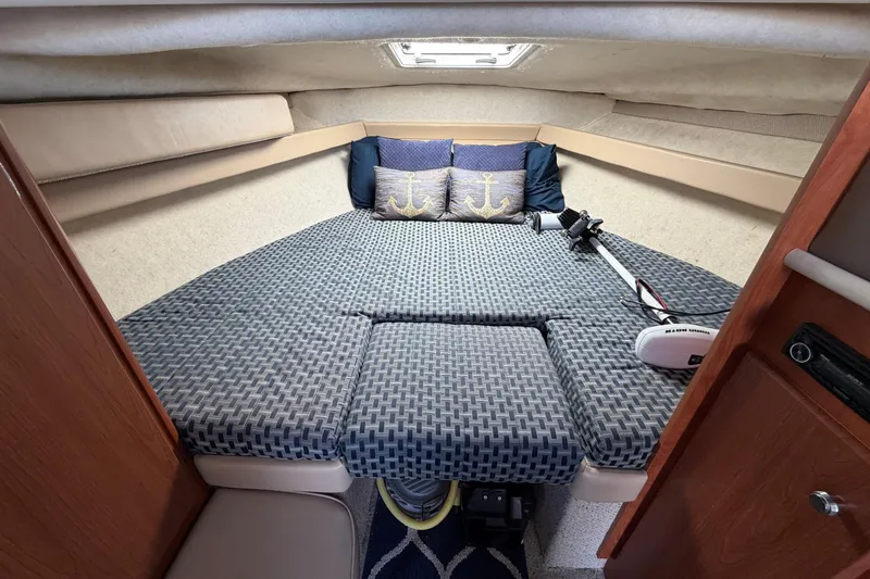 Slide: The Image of Cozy cabin interior of 2005 Bayliner 288 Classic with patterned bedding and nautical-themed pillows. - 10