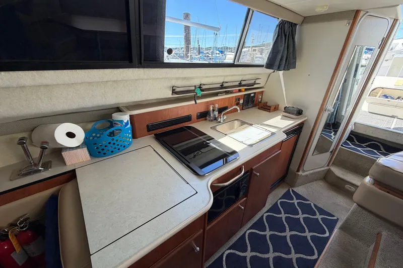 Slide: The Image of 2005 Bayliner 288 Classic boat interior with kitchenette, sink, and stove, docked at marina. - 4