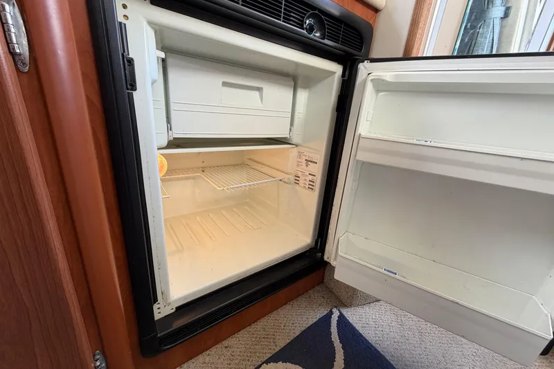Slide: The Image of Open refrigerator inside 2005 Bayliner 288 Classic boat, showing empty shelves and freezer compartment. - 6