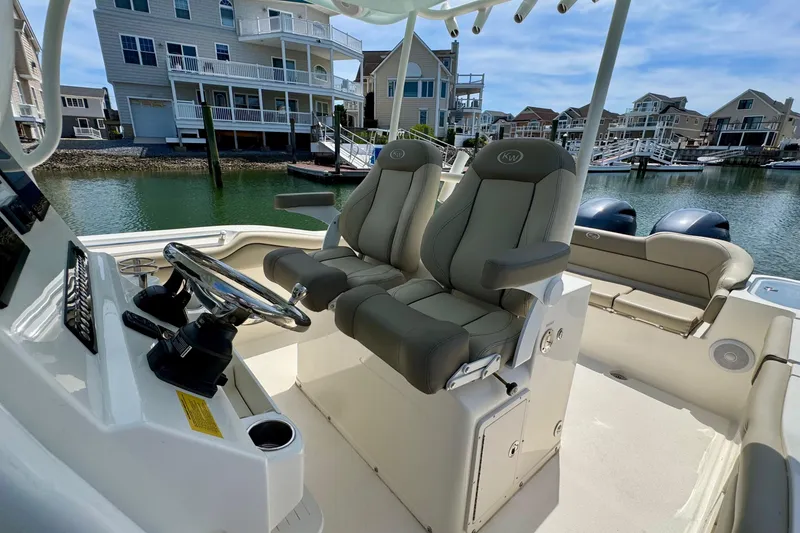 Slide: The Image of 2022 Key West 263 FS boat interior with dual seats and steering wheel in a marina setting. - 11