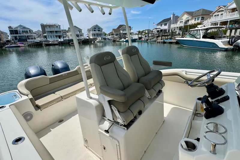 Slide: The Image of 2022 Key West 263 FS boat interior with seating and steering, docked in a marina. - 13