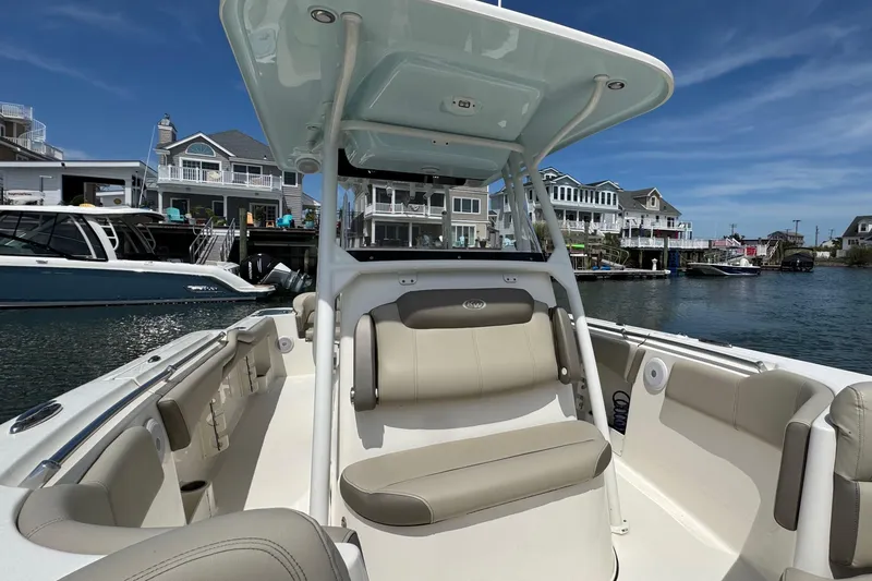 Slide: The Image of 2022 Key West 263 FS boat interior with seating, docked near waterfront homes. - 18