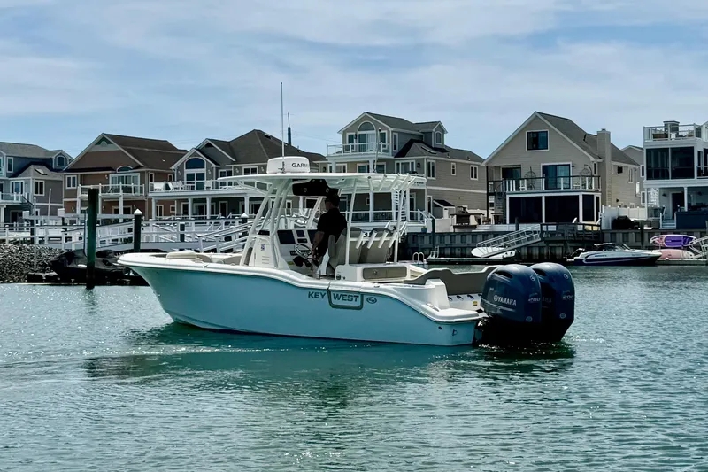 Slide: The Image of 2022 Key West 263 FS boat on water near waterfront homes, featuring twin Yamaha engines. - 2