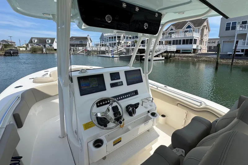 Slide: The Image of 2022 Key West 263 FS boat interior with modern dashboard, docked near waterfront homes. - 7