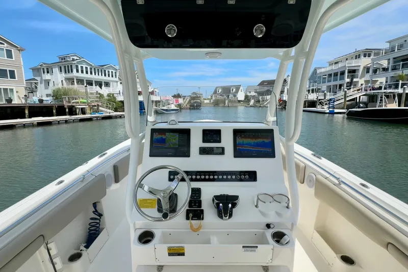 Slide: The Image of 2022 Key West 263 FS boat dashboard with modern navigation equipment, docked in a scenic marina. - 8
