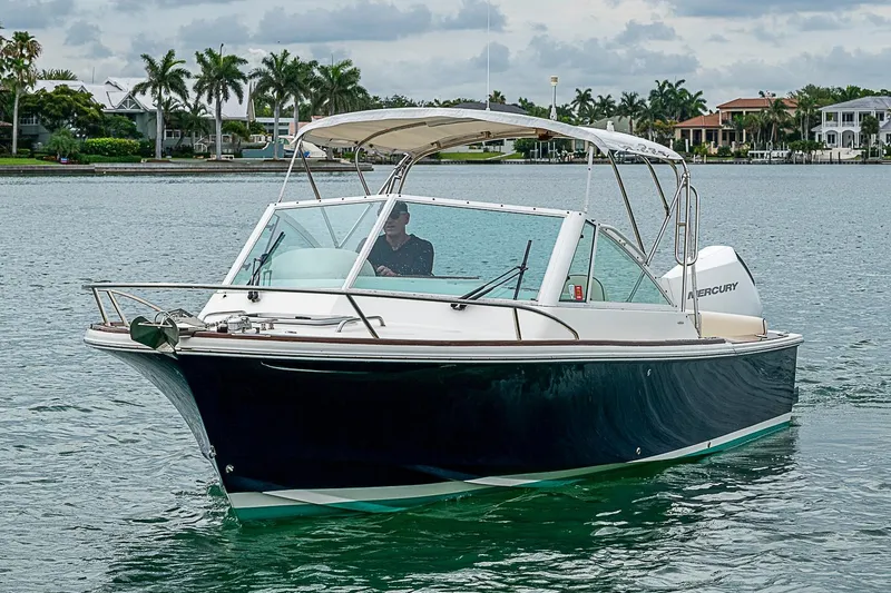 Slide: The Image of 2020 Hunt Yachts Harrier 26 cruising on a scenic waterway with palm trees in the background. - 2