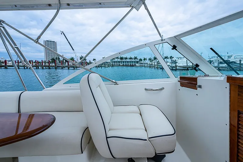 Slide: The Image of 2020 Hunt Yachts Harrier 26 interior with white seating, overlooking marina and palm trees. - 21