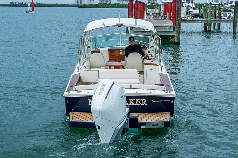Slide: The Image of 2020 Hunt Yachts Harrier 26 cruising near a dock, featuring a powerful outboard motor. - 5