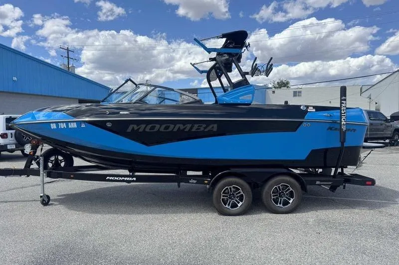 The Image of 2022 Moomba Kaiyen boat on trailer, blue and black design, parked outdoors. - 1
