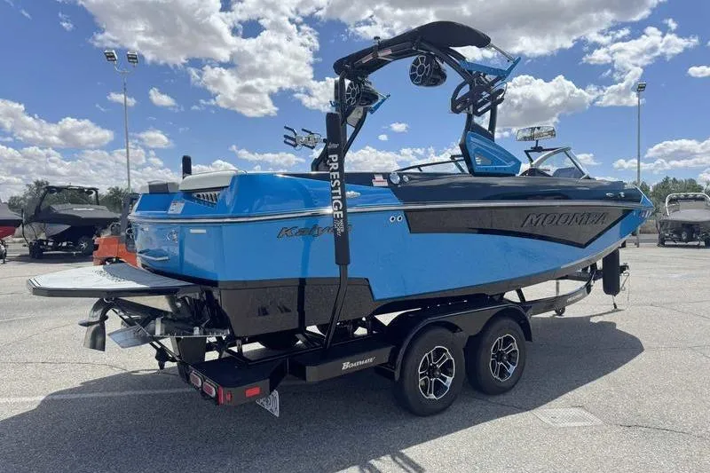 Slide: The Image of 2022 Moomba Kaiyen boat in vibrant blue on a trailer under a sunny sky. - 6