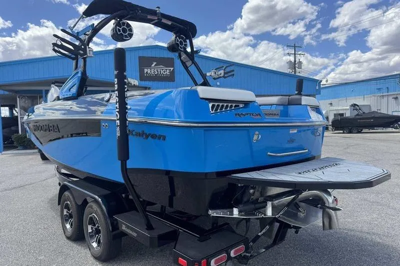 Slide: The Image of 2022 Moomba Kaiyen boat in vibrant blue, parked on a trailer at a dealership. - 8