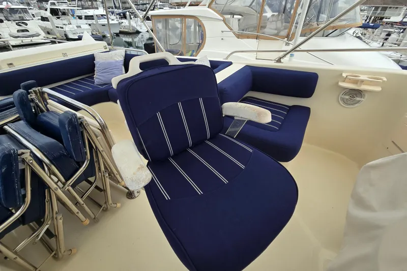Slide: The Image of 2008 Mainship 400 Trawler interior with blue seating and folding chairs in a marina setting. - 11