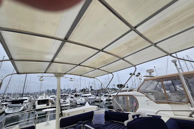 Slide: The Image of 2008 Mainship 400 Trawler docked in marina, featuring covered seating area and surrounding boats. - 12