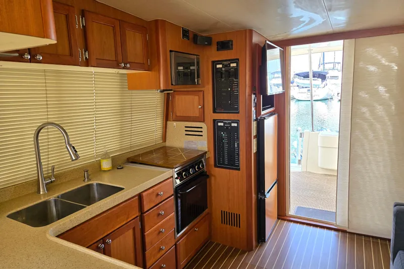 Slide: The Image of 2008 Mainship 400 Trawler kitchen with wood cabinetry, dual sink, and modern appliances. - 22