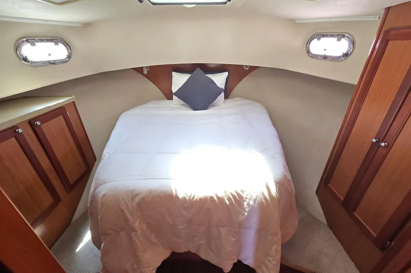 Slide: The Image of 2008 Mainship 400 Trawler cabin with cozy bed and wooden cabinetry. - 26