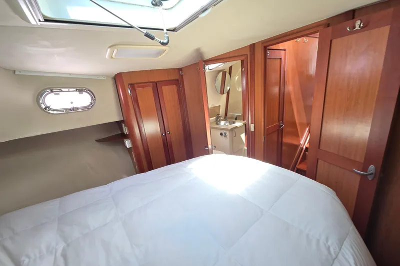 Slide: The Image of Interior cabin of 2008 Mainship 400 Trawler with bed, wooden doors, and porthole window. - 28