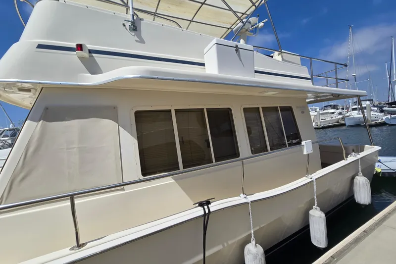 Slide: The Image of 2008 Mainship 400 Trawler docked at marina, side view with windows and fenders. - 5