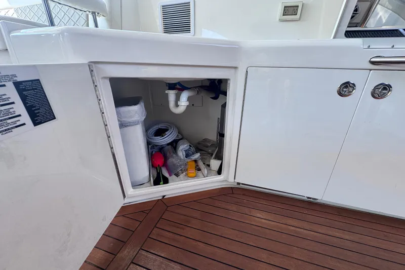 Slide: The Image of Open storage compartment on 2011 Sea Ray 540 Sundancer boat with various items inside. - 18