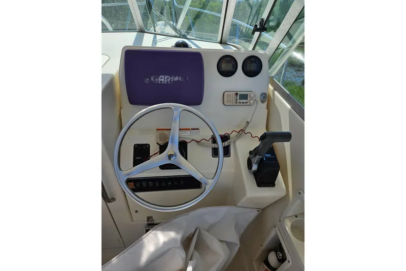 Slide: The Image of 2004 Pursuit 2470 Walkaround boat helm with steering wheel and control panel. - 3