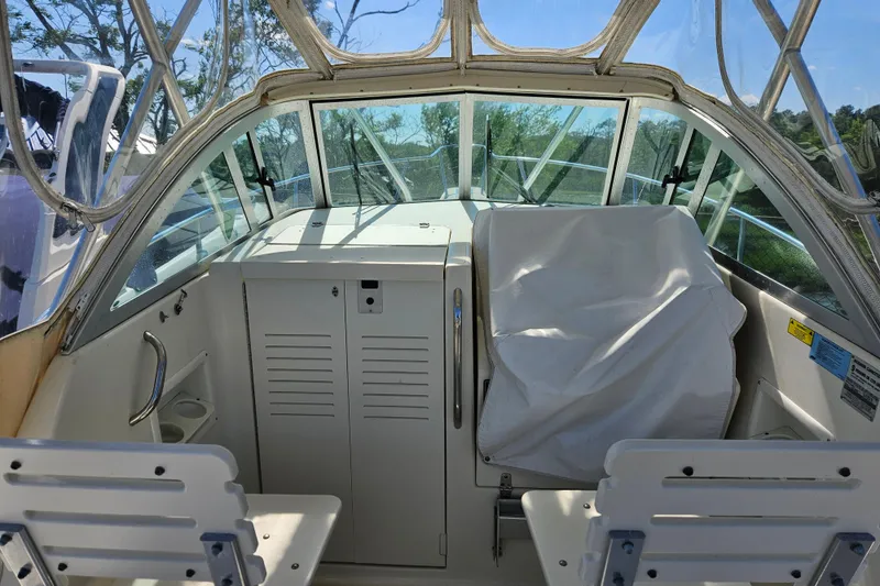 Slide: The Image of 2004 Pursuit 2470 Walkaround boat cockpit with covered seating and clear canopy. - 6