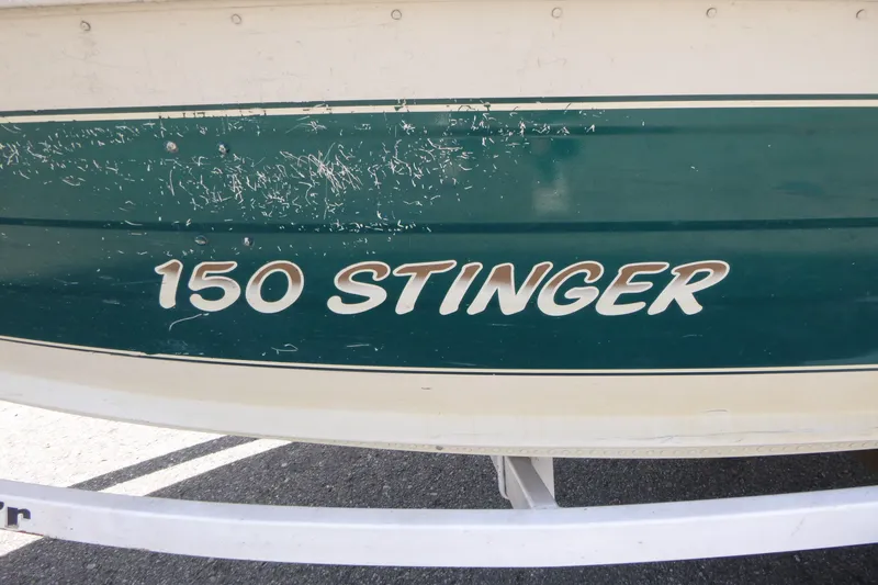 Slide: The Image of 1999 Smoker Craft 150 Stinger boat with visible scratches on the green hull. - 16
