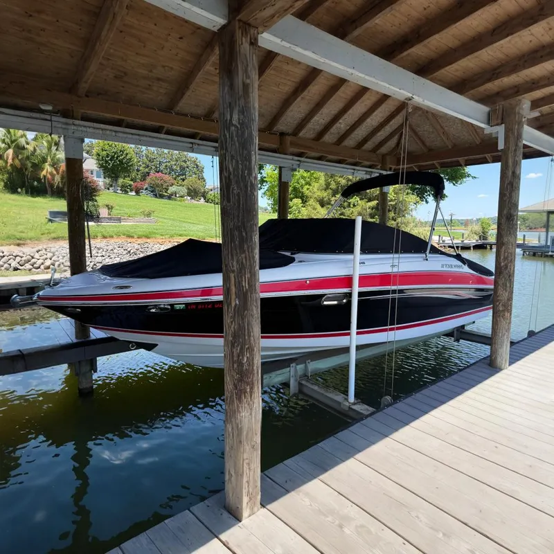 The Image of 2007 Four Winns H240 boat docked under a wooden canopy, covered and elevated above water. - 0