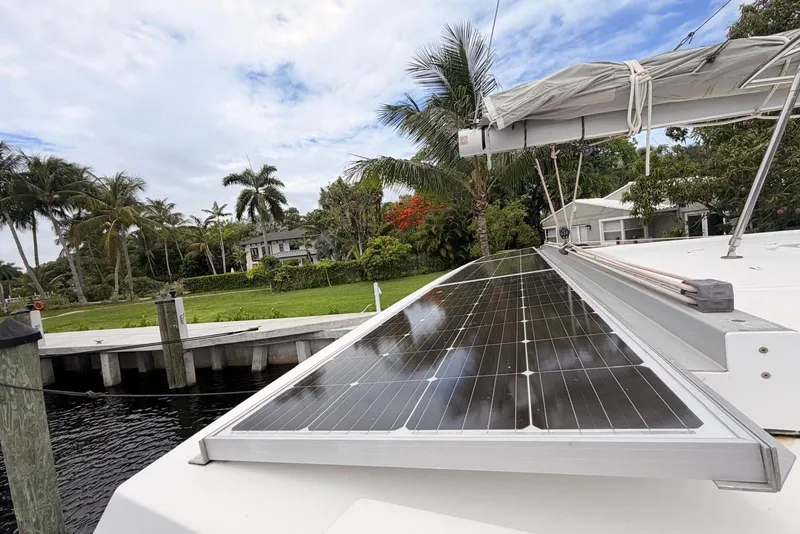 Slide: The Image of 2018 Fountaine Pajot Lucia 40 catamaran with solar panels, docked near lush greenery and palm trees. - 11