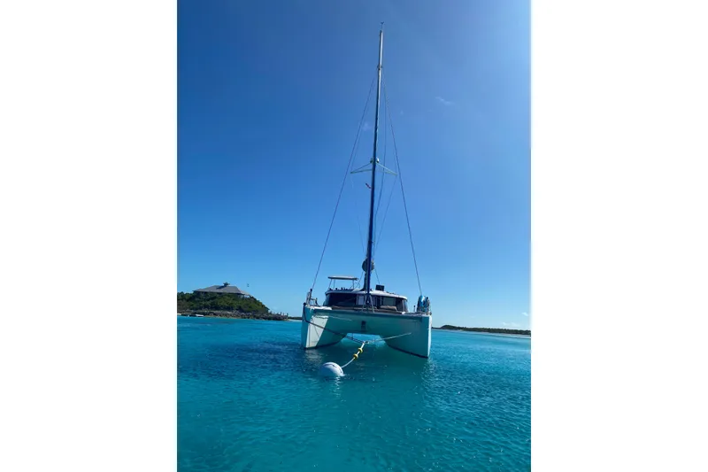 Slide: The Image of 2018 Fountaine Pajot Lucia 40 catamaran anchored in clear blue water. - 6