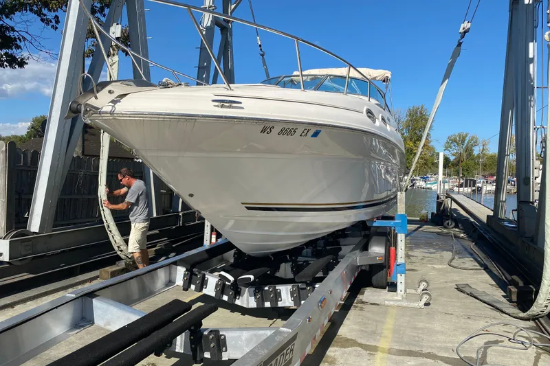 Slide: The Image of 2001 Sea Ray Sundancer 260 on trailer at marina, man securing boat. - 1