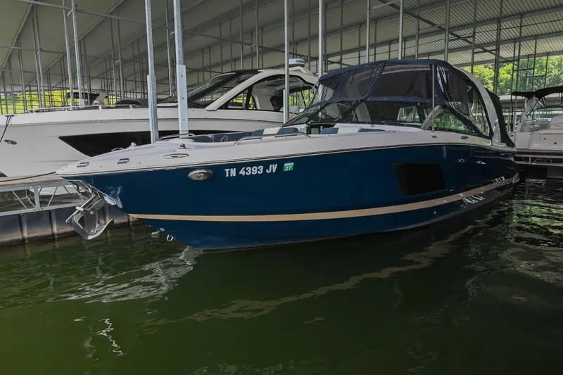 The Image of 2014 Four Winns H290 boat docked in a marina, featuring a sleek blue design. - 1