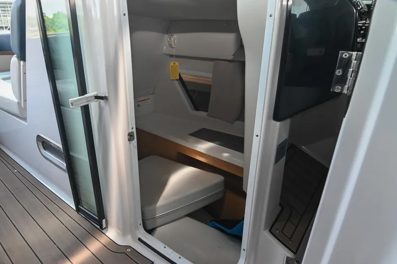 Slide: The Image of 2014 Four Winns H290 cabin interior with open door, showcasing seating and storage. - 23