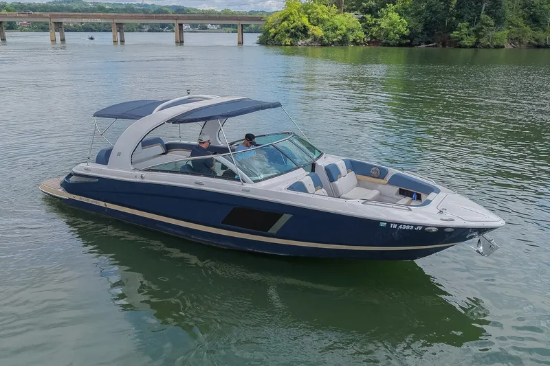 Slide: The Image of 2014 Four Winns H290 boat cruising on a serene lake with lush greenery. - 6