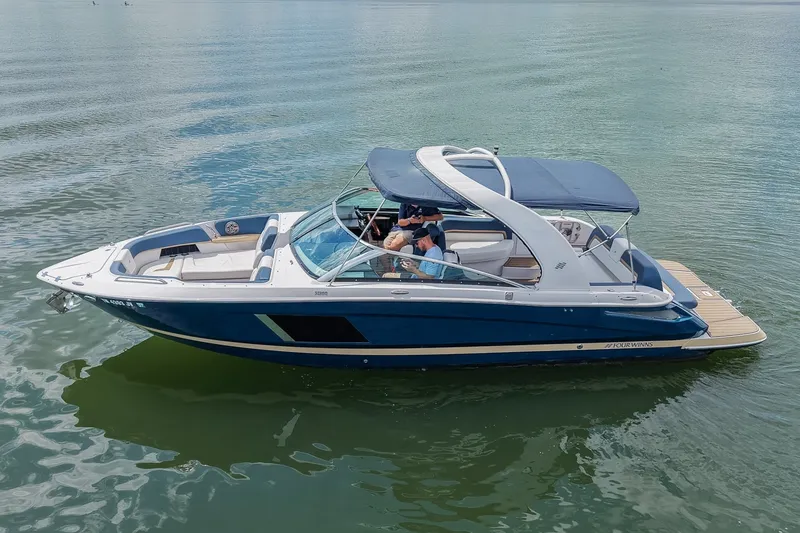 Slide: The Image of 2014 Four Winns H290 boat cruising on calm water with passengers onboard. - 4