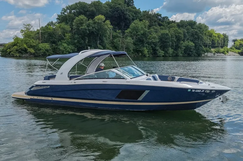 The Image of 2014 Four Winns H290 boat cruising on a scenic lake with lush green trees. - 0