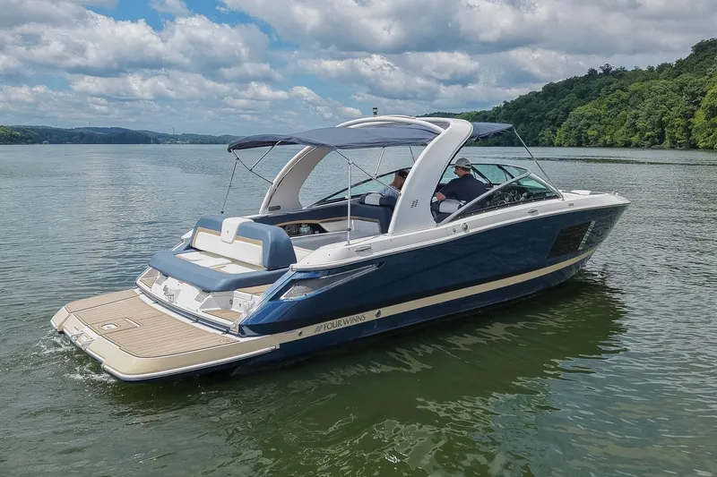 Slide: The Image of 2014 Four Winns H290 boat cruising on a scenic lake under a cloudy sky. - 2