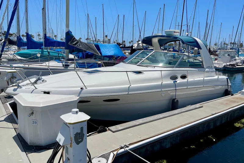Slide: The Image of 2000 Sea Ray Sundancer 310 docked at marina, surrounded by sailboats under clear blue sky. - 1