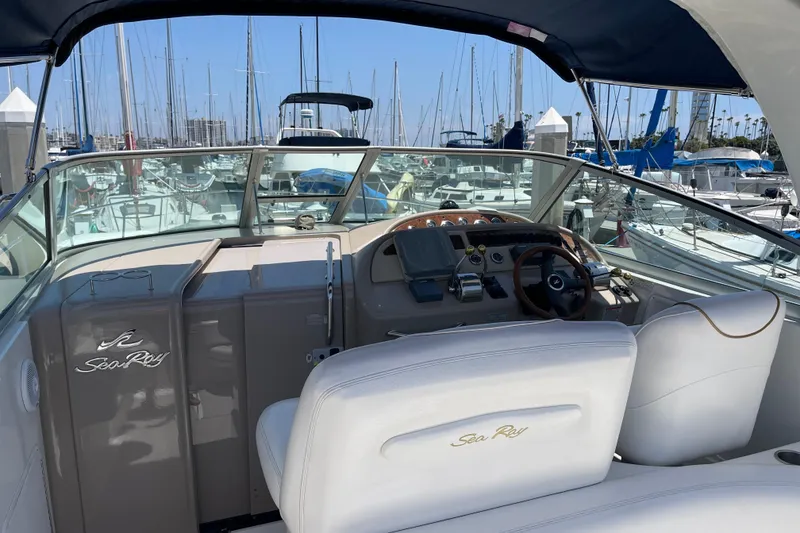 Slide: The Image of 2000 Sea Ray Sundancer 310 yacht cockpit with marina view, featuring elegant white seating and controls. - 12