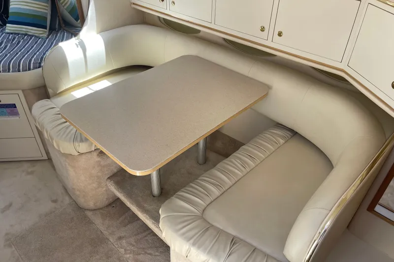 Slide: The Image of Interior of 2000 Sea Ray Sundancer 310 with cozy dining area and cushioned seating. - 15