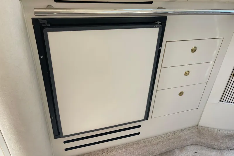 Slide: The Image of Interior view of a 2000 Sea Ray Sundancer 310, featuring a built-in refrigerator and storage drawers. - 18