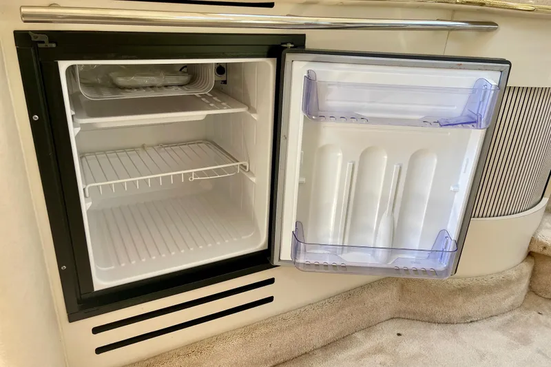 Slide: The Image of Compact refrigerator inside a 2000 Sea Ray Sundancer 310 boat, featuring open shelves and door storage. - 19