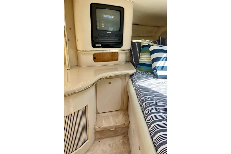 Slide: The Image of Interior of 2000 Sea Ray Sundancer 310 with TV, striped bedding, and cozy cabin space. - 24