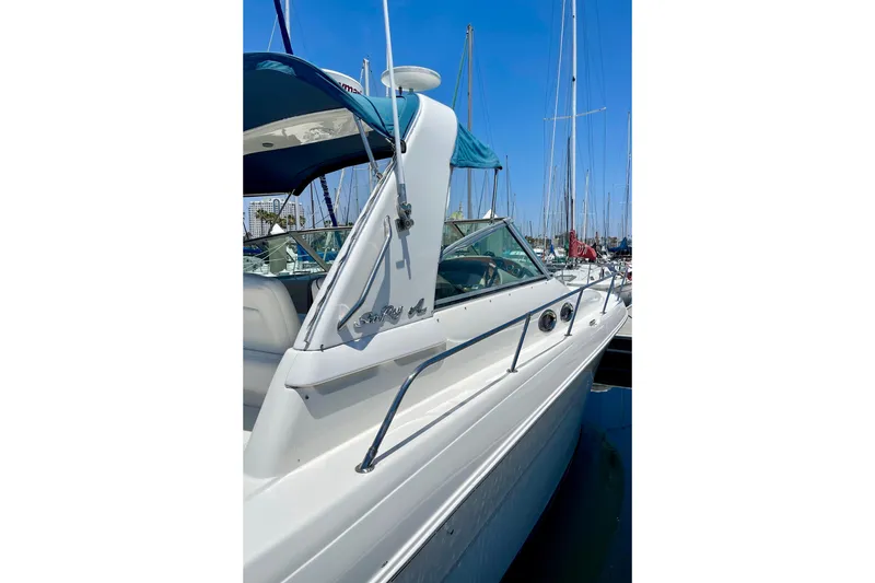 Slide: The Image of 2000 Sea Ray Sundancer 310 docked at marina, featuring sleek white design and blue canopy. - 6