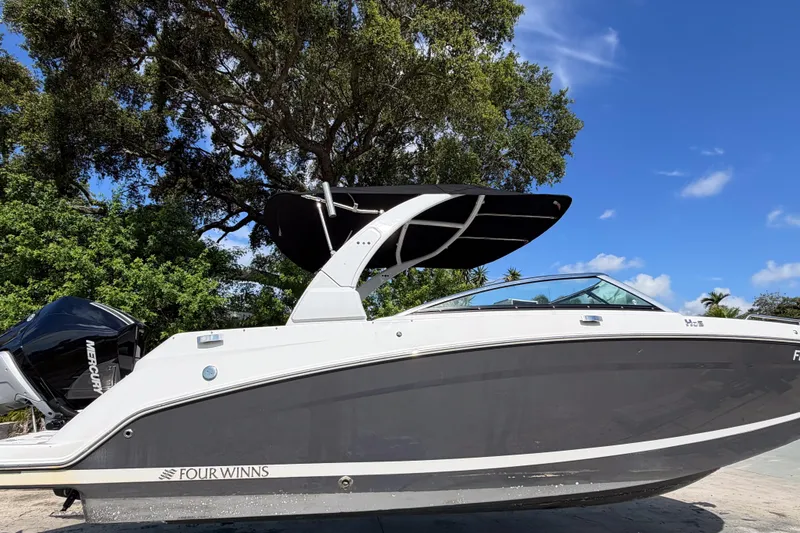 The Image of 2023 Four Winns HD5 OB boat with sleek design, parked outdoors under blue sky. - 0