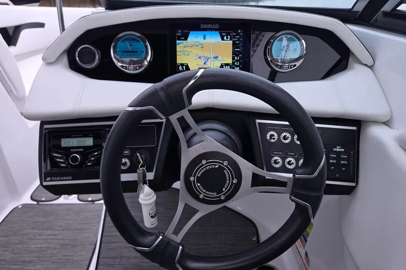 Slide: The Image of 2023 Four Winns HD5 OB boat dashboard with steering wheel and navigation controls. - 6