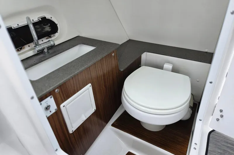 Slide: The Image of 2023 Four Winns HD5 OB boat bathroom with sink and toilet, featuring wood accents. - 7