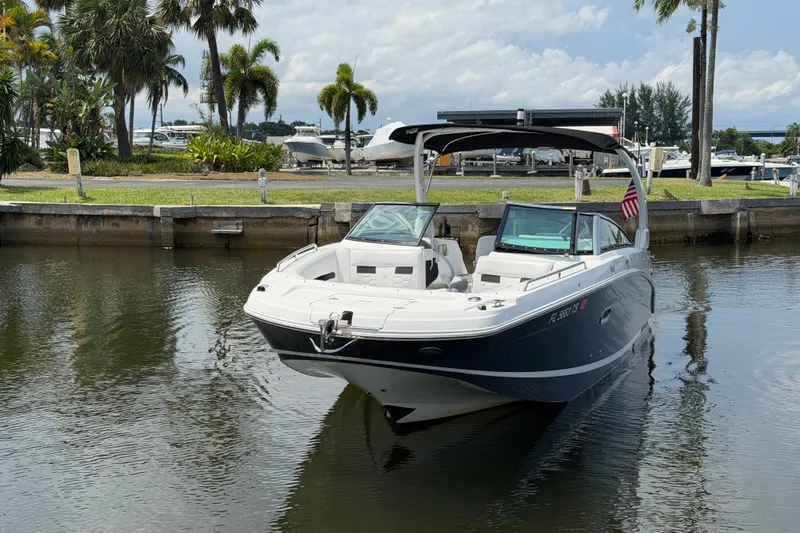 Slide: The Image of 2023 Four Winns HD5 OB boat docked on calm water with palm trees in background. - 9